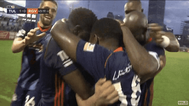 a group of soccer players huddle together in a huddle with a score of 1-0