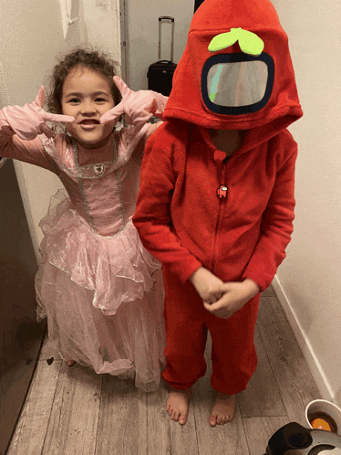 a girl in a pink dress and a boy in a red among us costume pose for a picture