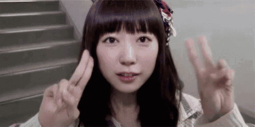 a young woman is giving a peace sign with her hands .