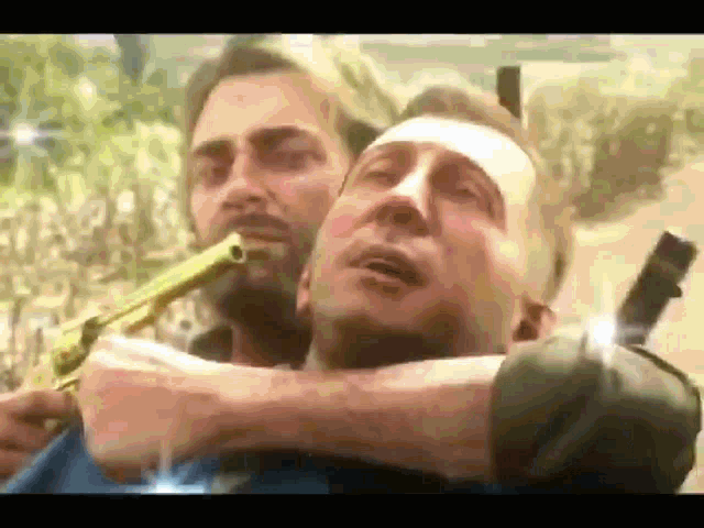 a man is holding a gun over another man 's head .