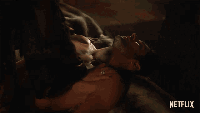 a shirtless man is laying on a bed with a netflix logo behind him