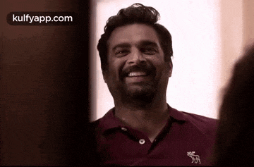 a man with a beard wearing a maroon polo shirt smiles