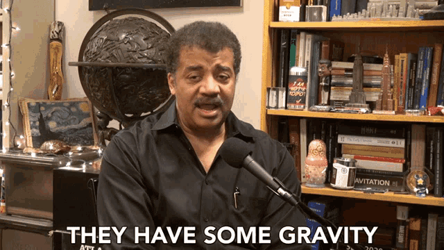 a man speaking into a microphone with the words " they have some gravity " next to him