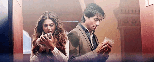 a man and a woman are standing next to each other in a room . the man is looking at his phone .