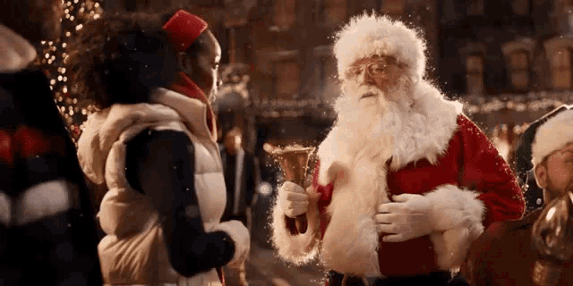 a man dressed as santa claus holding a bell