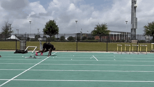 a man is running on a track with hurdles and a fence in the background