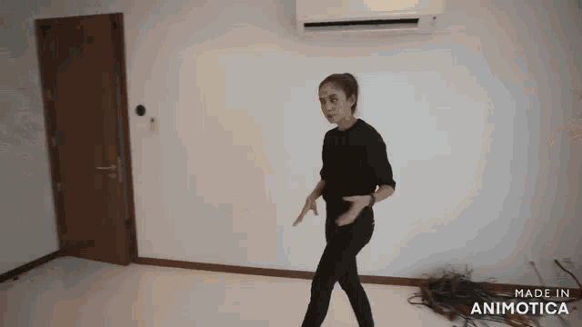 a woman in a black shirt and black pants is dancing in an empty room made in animatica