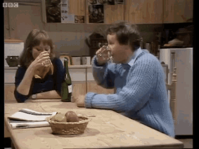 a man and woman are sitting at a table drinking wine