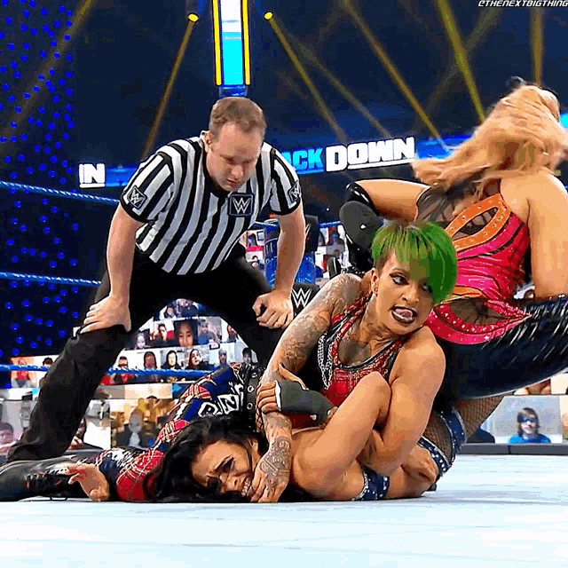a woman with green hair is wrestling another woman in a wrestling match