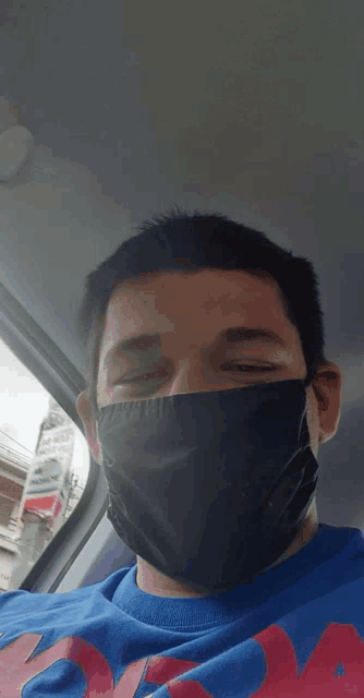 a man wearing a black face mask and a blue shirt with the letter a on the front