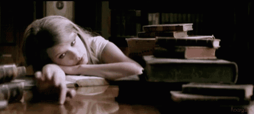 a girl is laying on a table with a stack of books on top of her