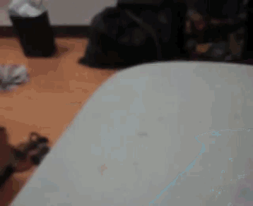 a blurred image of a room with a bed and a trash can .