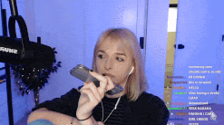 a woman wearing headphones holds a cell phone in front of a microphone that says shure