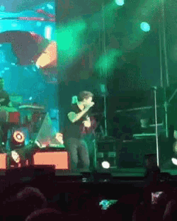 a man is singing into a microphone on a stage in front of a crowd