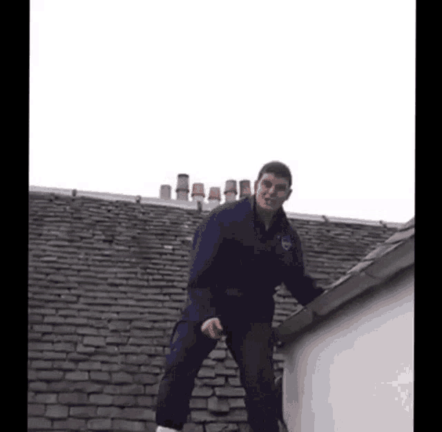 a man is standing on the edge of a roof looking down .
