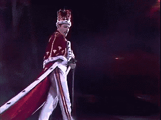 a man in a crown and robe is standing on a stage holding a sword .