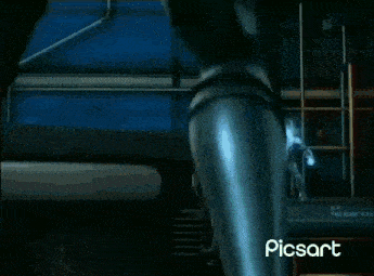 a robot is standing in a dark room with a blue light coming out of it 's chest .