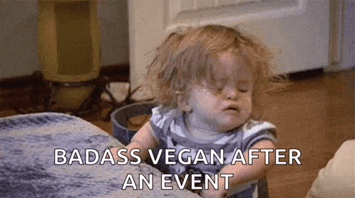 a little girl is sitting on a bed with her eyes closed and the words badass vegan after an event .