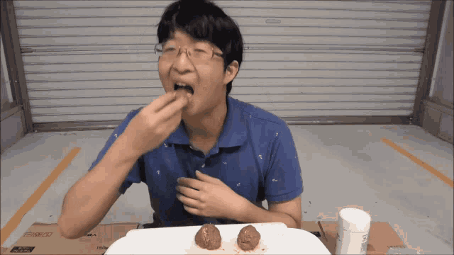 a man in a blue shirt is eating a piece of food from a cardboard box