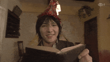a man wearing a party hat looks at a book