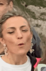 a woman wearing earrings is making a funny face while standing next to a group of people .