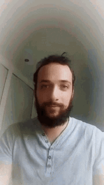 a man with a beard is wearing a light blue shirt