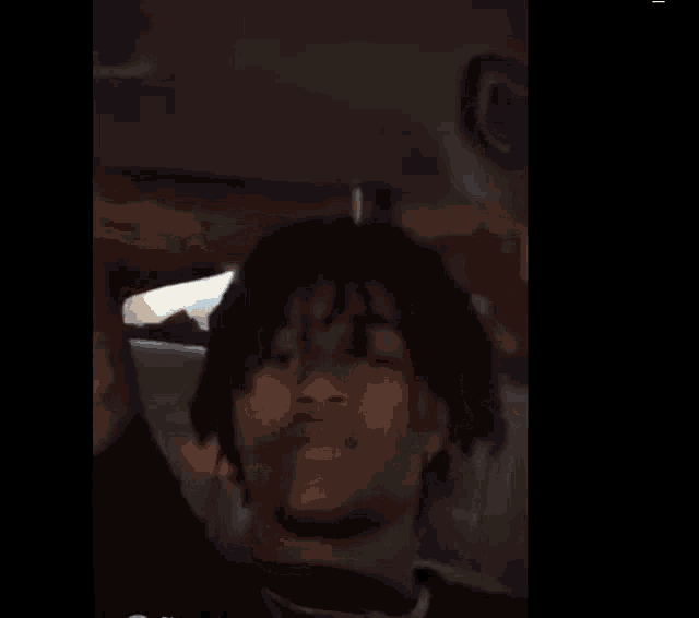 a young man with dreadlocks is sitting in the back seat of a car looking out the window .