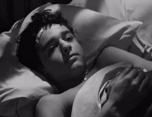 a young boy with a bandage on his forehead is laying in bed