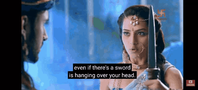 a woman is holding a sword and talking to a man in a video .