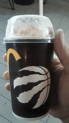 a person is holding a cup with a basketball and a claw on it