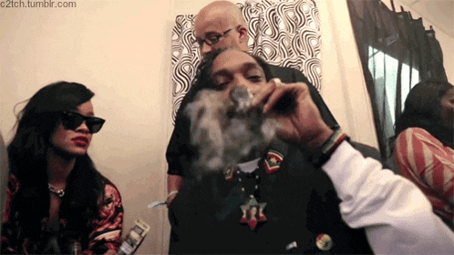 snoop dogg is smoking a cigarette in a room with two other people