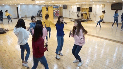 a group of young girls are dancing and singing in a dance studio