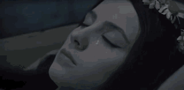 a woman with a flower crown on her head is laying in bed with her eyes closed