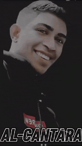 a man is smiling and wearing a black jacket with the word al-cantara written on it .