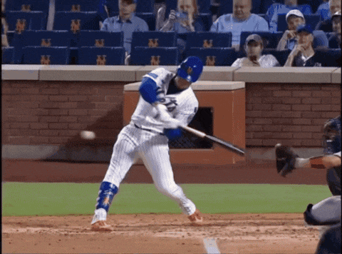 a baseball player swings his bat at a ball in front of a wall with ny on it