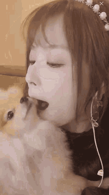 a woman with a pearl tiara on her head kisses a small dog