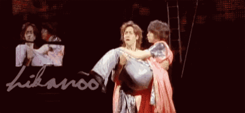 a man is holding a woman in his arms on a stage .