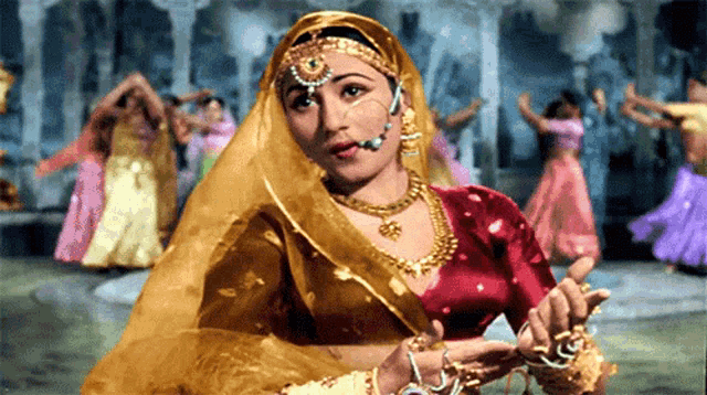 a woman in a red and gold dress is dancing with other women