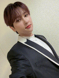 a young man in a suit and white shirt is taking a selfie with his phone .