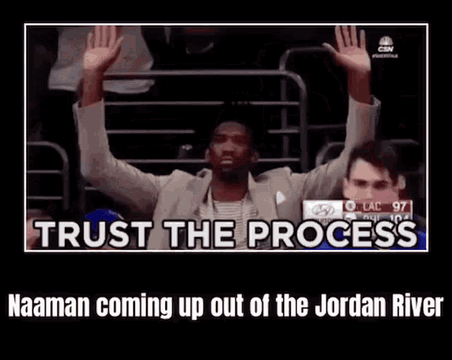 a man in a suit is sitting in a stadium with his arms in the air and a caption that says trust the process