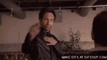 a man in a leather jacket is standing next to another man in a room and talking to him .