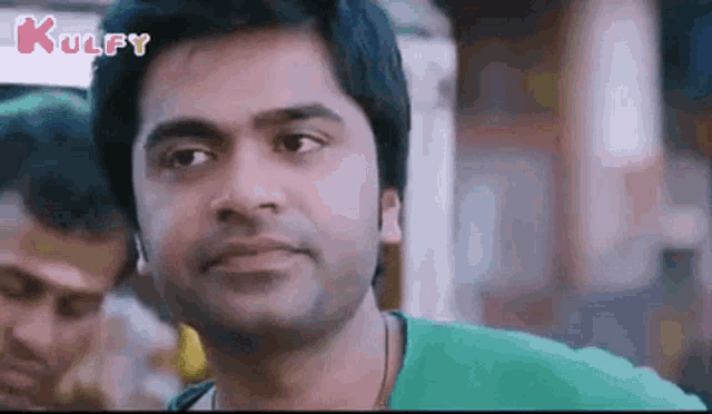 a man in a green shirt is making a funny face in a movie .