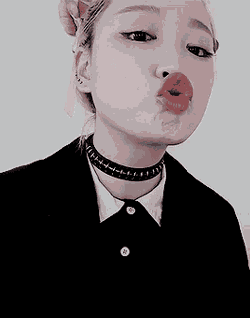 a woman wearing a choker and a black jacket is making a face