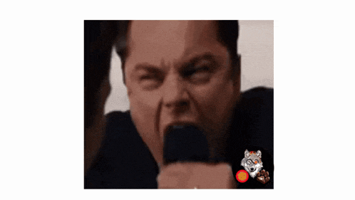 a man is making a funny face while holding a microphone in his hand .