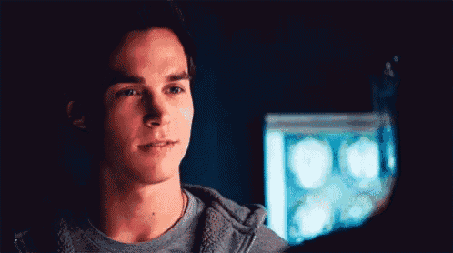 a young man is standing in front of a computer screen and looking at it .