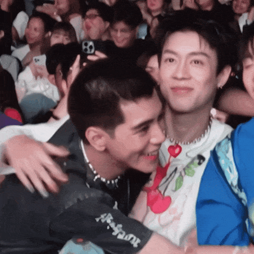 a man wearing a shirt that says ' elephant ' on the arm is hugging another man