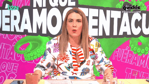 a woman sits at a table in front of a sign that says " eram tentacu "