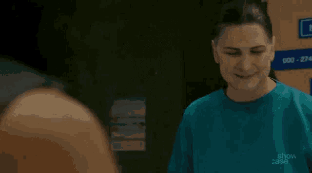 a woman in a blue shirt is standing next to a man in a room and smiling .