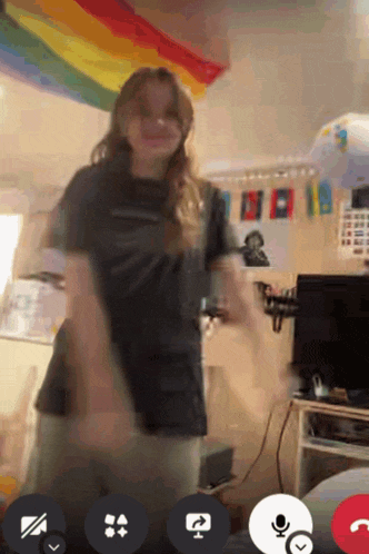 a girl is dancing in front of a rainbow flag in a room