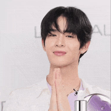 a young man making a heart shape with his hands in front of a sign that says l' oreal